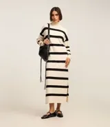 Vestido midi de punto con cuello alto y mangas largas. Diseño recto con rayas horizontales negras sobre fondo crudo y aberturas laterales.