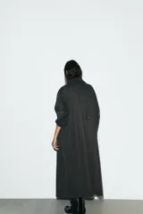 Gabardina larga color gris oscuro con efecto encerado, cuello solapa de pana, manga larga, bolsillos laterales con solapa y cierre frontal con botones ocultos.