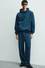 Sudadera con capucha de corte relajado, confeccionada en tejido de algodón con interior perchado. Presenta mangas largas, bolsillo frontal tipo canguro y terminaciones en rib.