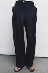 Pantalón de tiro alto con pernera recta, confeccionado en denim oscuro. Presenta nervios marcados en el delantero, bolsillos frontales tipo parche y cierre frontal con cremallera y botón.