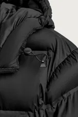 Cazadora puffer acolchada de corte relaxed fit color negro, confeccionada en tejido técnico repelente al agua. Cuenta con cuello subido, capucha ajustable con elásticos y cierre frontal con cremallera. Tiene bolsillos de vivo en la cadera, bolsillo interior y mangas largas con puños elásticos ajustables con abertura para el dedo pulgar.