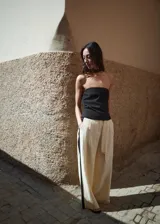Pantalón wide leg de lino color beige con franjas negras en contraste a los costados, tiro alto, bolsillos laterales y cinturón incorporado.