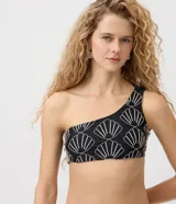 Top de bikini asimétrico de un solo hombro, color negro con bordado de conchas en tono claro, confeccionado en poliamida y elastano con forro de poliéster.