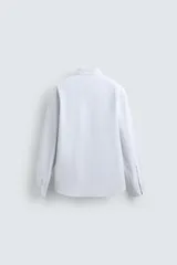 Camisa de corte regular fit confeccionada en tejido de algodón con diseño de rayas finas. Presenta cuello solapa, cierre frontal de botones y manga larga con puños abotonados.