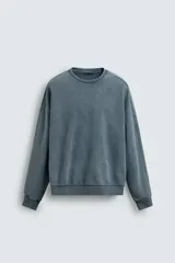 Sudadera de corte relaxed fit confeccionada en tejido de algodón con interior de rizo. Presenta cuello redondo, manga larga y acabados en rib, con un acabado de efecto lavado que le otorga una apariencia única.