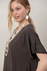 Remera negra de algodón con cuello redondo, mangas cortas y zócalo de satén desflecado en el ruedo y las mangas.