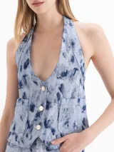 Chaleco de denim de algodón con diseño estampado de efecto desgastado, escote en V pronunciado, cierre frontal con botones y bolsillos frontales.