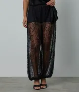 Pantalón de encaje negro con diseño aladín, de corte amplio y fluido con cintura elástica. Presenta una estructura transparente en las piernas y forro corto en la parte superior.