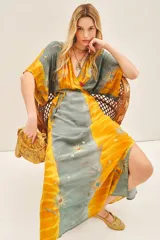 Vestido largo con estampado floral y bordados en hilo de lurex, en tonos amarillo y verde. Presenta mangas anchas al codo, escote en V y ajuste elástico en la cintura.