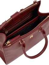 Cartera tote de Tommy Hilfiger color borgoña, con doble asa de mano y correa larga extraíble y ajustable. Tiene cierre magnético, dos compartimentos principales y tres bolsillos interiores con cremallera.