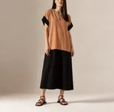 Vestido largo de diseño bicolor en tonos tostado y negro, con cuello en V, mangas cortas con vuelta negra y corte recto y holgado.