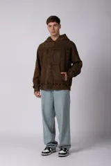 Buzo canguro oversize con efecto lavado desgastado, confeccionado en friza pesada. Presenta diseño con recortes, capucha amplia y puños y ruedo acanalados.