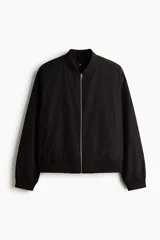 Campera bomber liviana color negro, con cuello, puños y dobladillo acanalados, cierre frontal metálico y bolsillos laterales ribeteados.