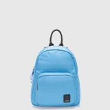 Mochila pequeña de diseño acolchado con costuras horizontales, color celeste. Cuenta con un compartimento principal con cierre, un bolsillo frontal con cierre, asa superior negra y correas ajustables. Incluye detalle de etiqueta con logo de la marca en la parte inferior.