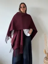 Ruana gris de tejido de punto con flecos en el ruedo.