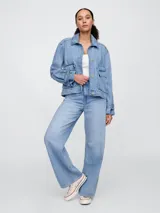 Campera de jean en tono azul claro, con diseño utility que incluye bolsillos frontales con solapa, cierre frontal con botones y puños ajustables con botón.