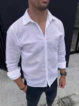 Camisa de lino color blanco off white, de manga larga, con cuello clásico y cierre frontal de botones.