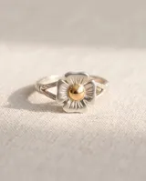 Anillo de plata con diseño de flor y detalle central dorado.