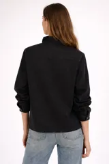 Campera de algodón color blanco, con cuello alto con volados, cierre frontal de botones plateados, mangas largas y cuatro bolsillos frontales.