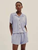 Camisa celeste de tela de toalla con cuello tipo polo, manga corta y botones de madera. Estilo unisex.