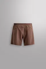 Short deportivo de entrenamiento en color marrón, confeccionado en tejido técnico ligero y elástico. Cuenta con cintura elástica ajustable con cordón, bolsillos frontales, bolsillo trasero con cierre y aberturas laterales en el bajo. Incluye un pequeño detalle de logo estampado en la pierna.