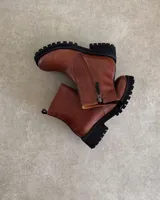 Botín de cuero color marrón con suela track negra y cierre lateral.