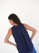 Top sin mangas color azul marino, con escote a la base y detalle de lazos en el cuello.