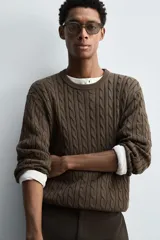 Jersey de punto color marrón oscuro, con cuello redondo y manga larga. Presenta un tejido con estructura de ochos y acabados en rib.