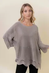 Buzo de tejido liviano con brillo sutil tipo lurex, color beige o dorado claro. Presenta un calce suelto (oversize) con mangas amplias y cuello redondo. El ruedo tiene un detalle de terminación festoneado con pequeños calados.