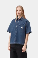 Camisa de denim de algodón celeste, de corte holgado y mangas cortas, con cierre frontal de botones metálicos y un bolsillo aplicado en el pecho con etiqueta de la marca.