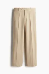Pantalón de vestir de corte regular, color beige, con pliegues frontales, cierre de cremallera, pretina con botón y bolsillos laterales y traseros ribeteados.