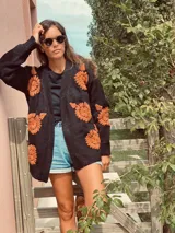 Cárdigan negro de lana merino con bordados de flores color naranja.