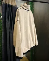 Buzo de pana color beige con cuello polo, cierre frontal parcial y forro interior de corderito. Presenta diseño oversized, bolsillos laterales y puños elásticos.