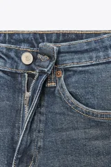 Jeans de tiro alto color marrón oscuro con acabado lavado, corte recto/flare y bajo cropped sin costuras. Presenta cinco bolsillos y cierre frontal con cremallera y botón metálico.