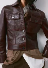 Chaqueta de cuero bordó con cierre frontal de botones, bolsillos con solapa en el pecho y cuello camisero.
