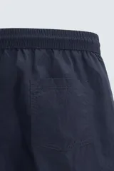 Short de baño de color azul marino, confeccionado en tejido técnico, con cintura elástica ajustable mediante cordón, bolsillos laterales y detalle de bolsillo trasero.