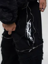 Pantalón de jean estilo baggy fit, color negro, con diseño de costuras visibles y cierres laterales que permiten convertirlo en bermuda. Presenta estampado serigráfico en los laterales.