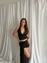 Top negro de creppe con cuello halter y escote pronunciado drapeado.