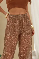 Pantalón largo color marrón con tejido de red transparente y apliques de brillos plateados, de tiro alto y corte ancho.