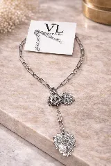 Collar de cadena plateada de eslabones alargados con dijes colgantes. Incluye un dije de corazón texturado con incrustaciones de strass, un dije de ojo con diseño solar y un dije circular con strass.