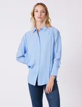 Camisa de algodón con estampado de rayas verticales finas en color azul claro. Tiene cuello con solapa, escote en V y cierre frontal con botones.