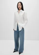 Camisa de corte oversize confeccionada en tejido popelín de mezcla de algodón y lyocell. Presenta diseño recto, cuello camisero, cierre frontal con botones y manga larga con puños abotonados. Incluye un sutil detalle bordado en el pecho.