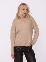 Sweater color beige de tejido de punto con cuello redondo y mangas largas con detalle de costuras blancas en los hombros.