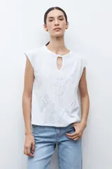 Remera de manga corta color verde petróleo, con cuello redondo y detalle de abertura tipo gota en el frente. Presenta un diseño con bordados geométricos tono sobre tono en la parte frontal.
