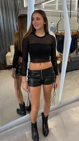 Top de manga larga confeccionado en tul negro transparente, con cuello redondo y terminaciones con borde ondulado.