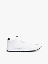 Zapatillas deportivas Tommy Hilfiger de corte bajo, inspiradas en modelos clásicos de running. Presentan un exterior en mezcla de piel blanca con paneles de texturas mixtas, detalles de ventilación en la parte superior y suela de goma con tacos. Incluyen cordones y logo de la marca en el lateral, lengüeta y parte trasera.