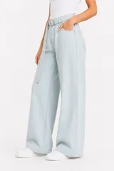 Pantalón jean de tiro alto y corte ancho, color celeste claro, con bolsillos laterales y cinto de la misma tela con hebilla metálica circular doble.