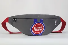 Riñonera gris con correa roja ajustable, logo de la NBA y escudo de los Detroit Pistons.