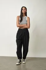 Pantalón negro de tiro alto y corte amplio, con pinzas en la cintura y bolsillos laterales.