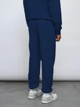 Pantalón jogger de felpa sin frisa, color gris claro melange, con logo bordado de Umbro en azul oscuro en el muslo izquierdo y puños elásticos en los tobillos.